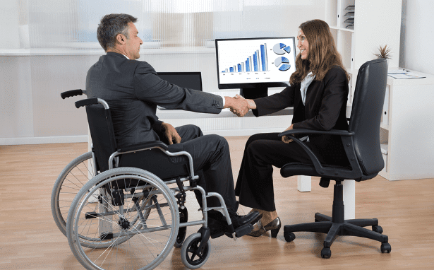 Disability Inclusion in Employment - Man in wheel chair shaking hands with colleague