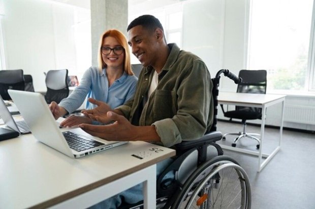 Male in wheelchair and female looking at a laptop