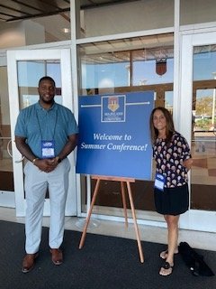 Kevin Walker and Mary Manzoni of Maryland Works Inc. post in front of a sign saying 'Welcome to Summer Conference!" for the Maryland Association of Counties Summer 2023 Event.